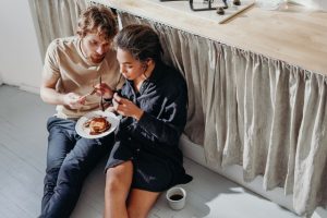 man and woman sitting next to table eating chocolate pancakes